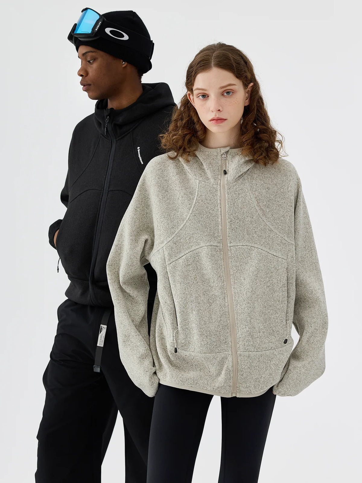 Two models wearing full-zip melange knit fleece jackets in grey and black